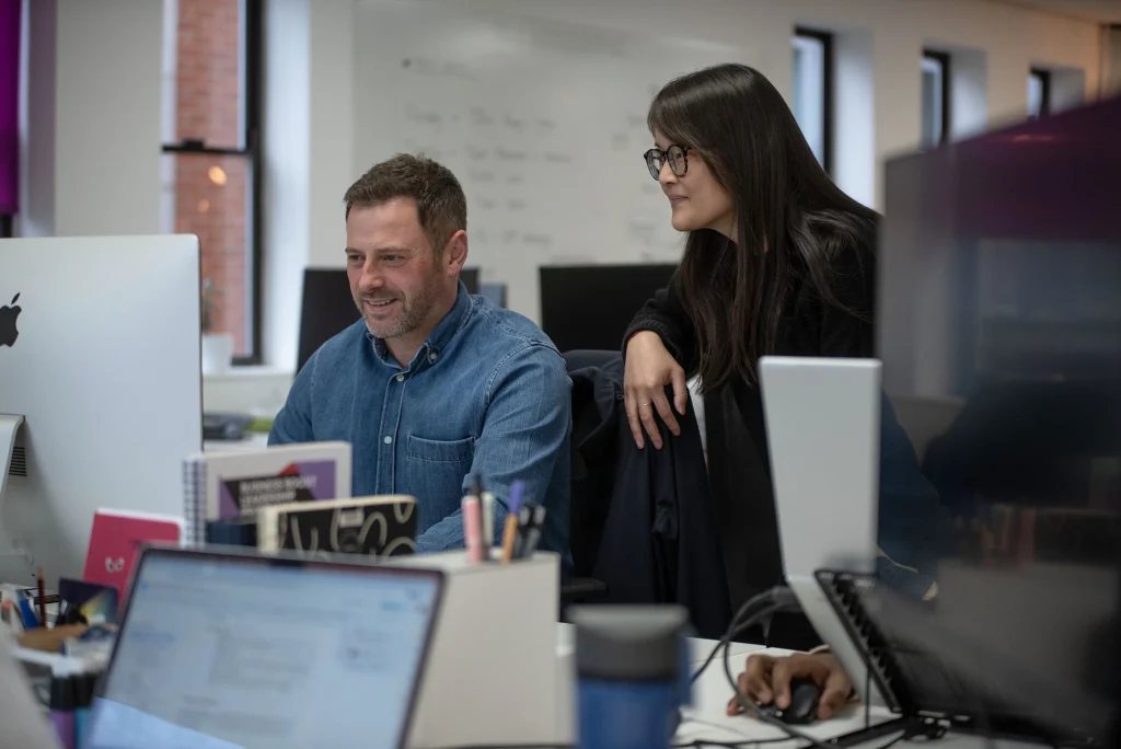 Two colleagues in an Agency looking at a computer monitor together in an office